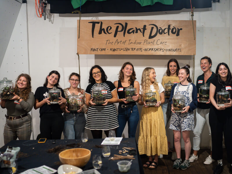 A group of women smiling holding terrariums